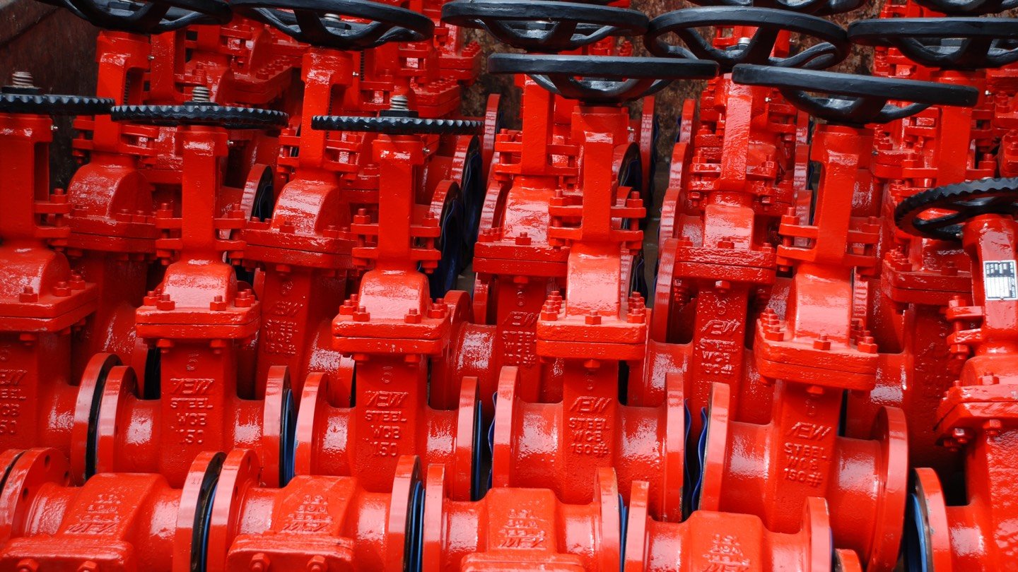 Rows of red flanged gate valves stored on an industrial rack.